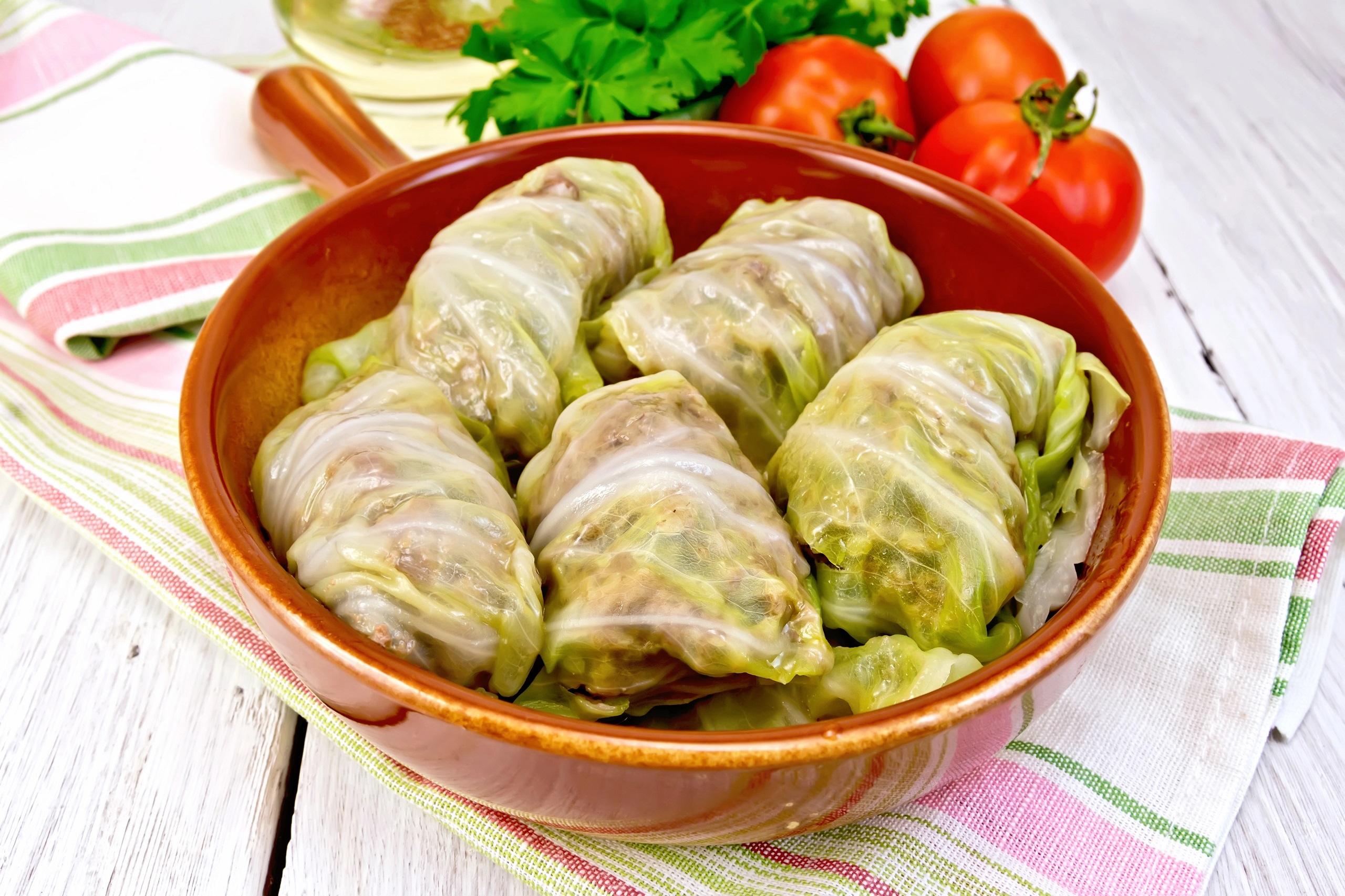 Freshly made gołąbki stuffed with meat and rice in a ceramic brown pan on a linen kitchen cloth