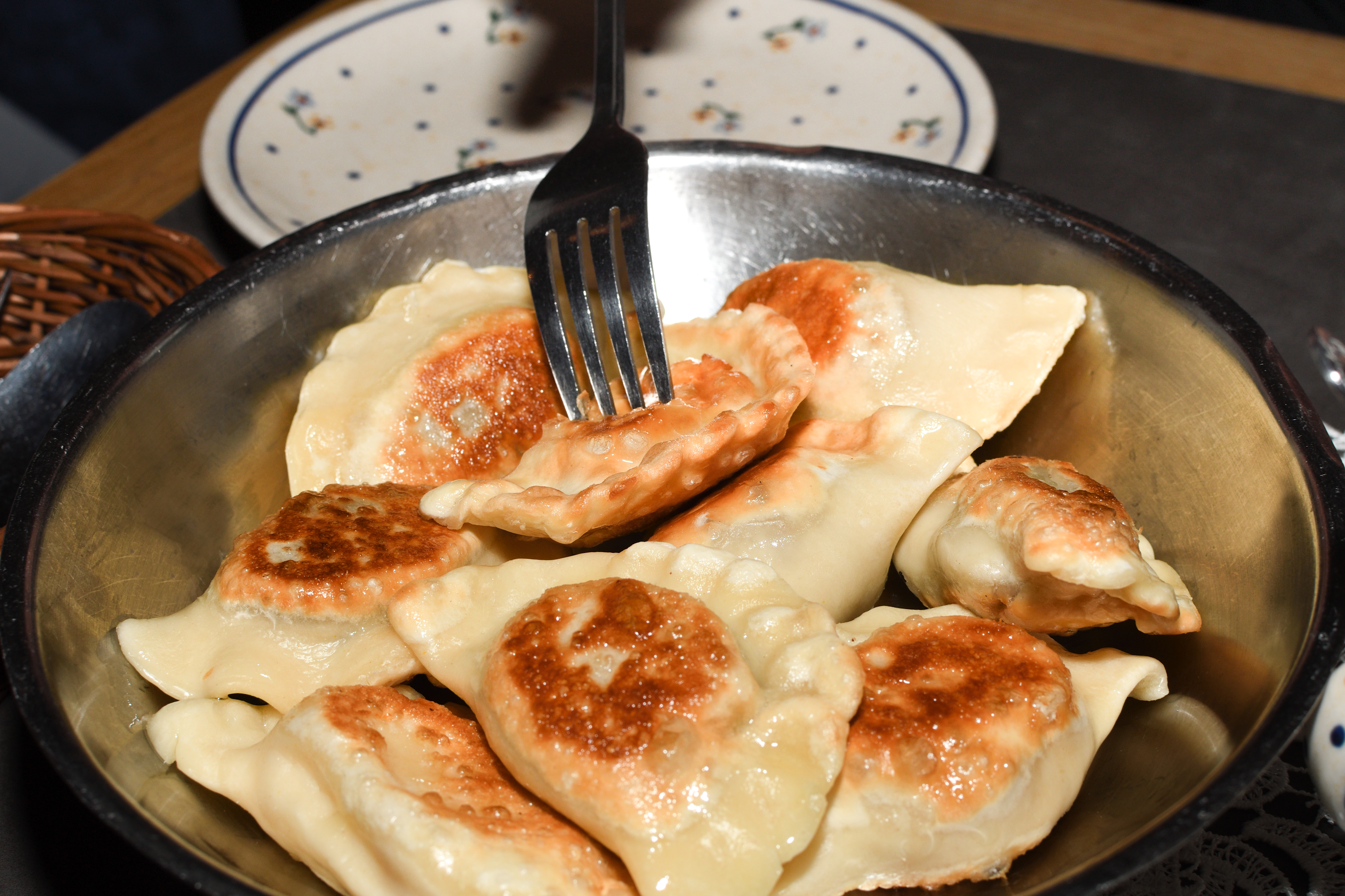 Fried meat pierogies in a pan with a fork stuck in one