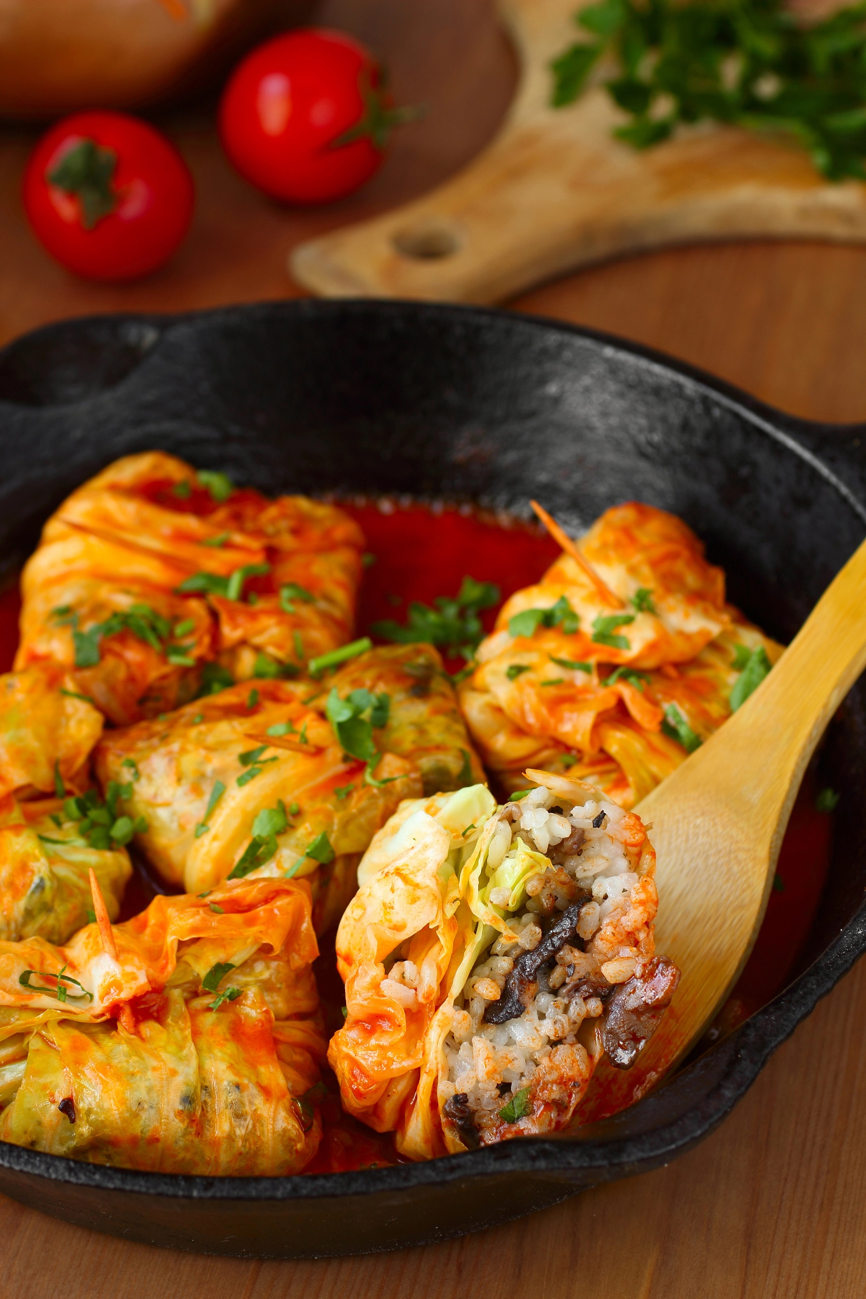 Polish gołąbkis stuffed with mushrooms, herbs and rice each rolled in a cooked cabbage leaf garnished with parsley just made in an iron skillet still simmering in their tomato juices.