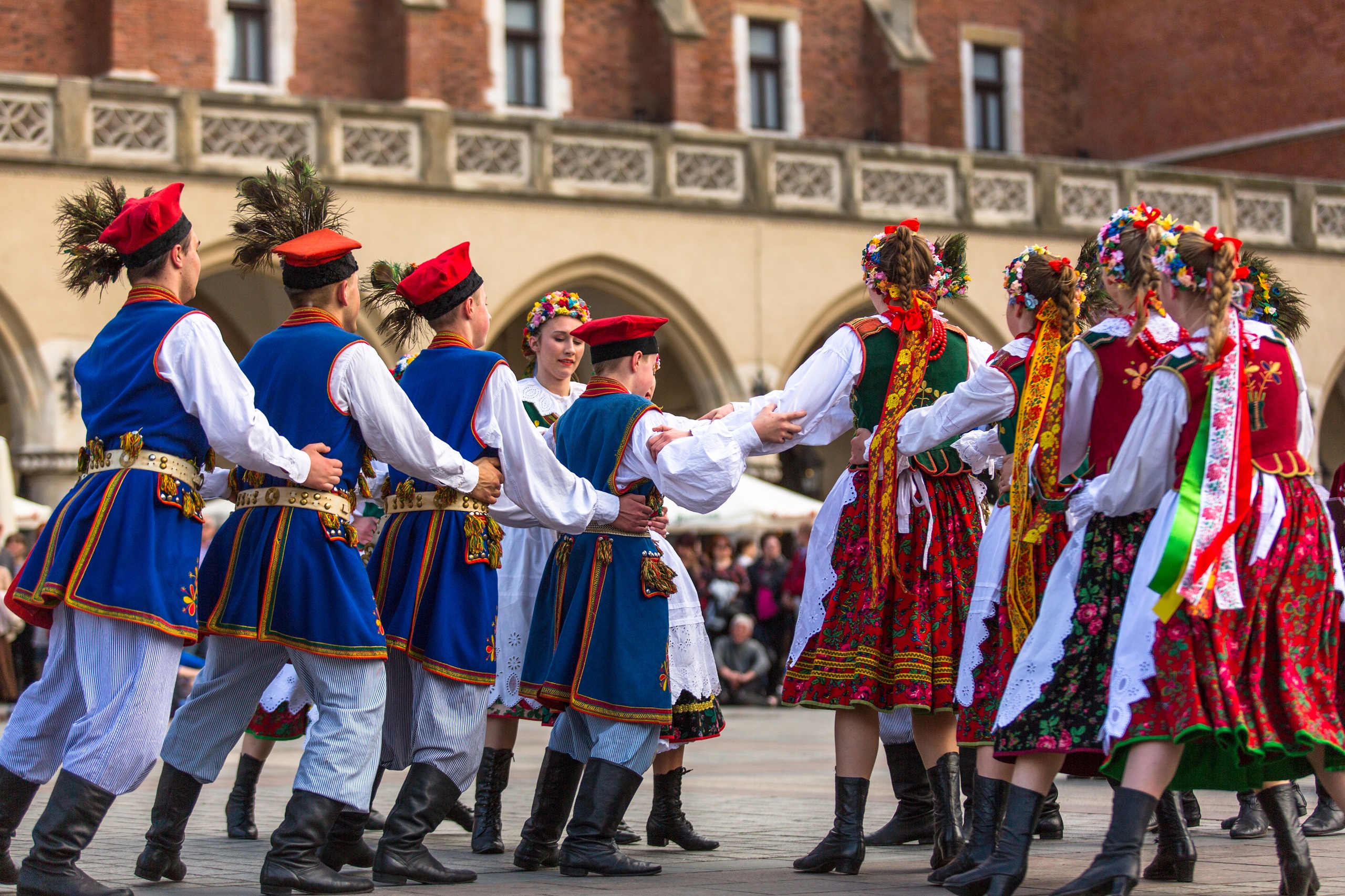 Boys and girls of different ages dancing a traditional Polish dance in Polish folklore costumes in the Old Town Square located in Krakow, Poland.