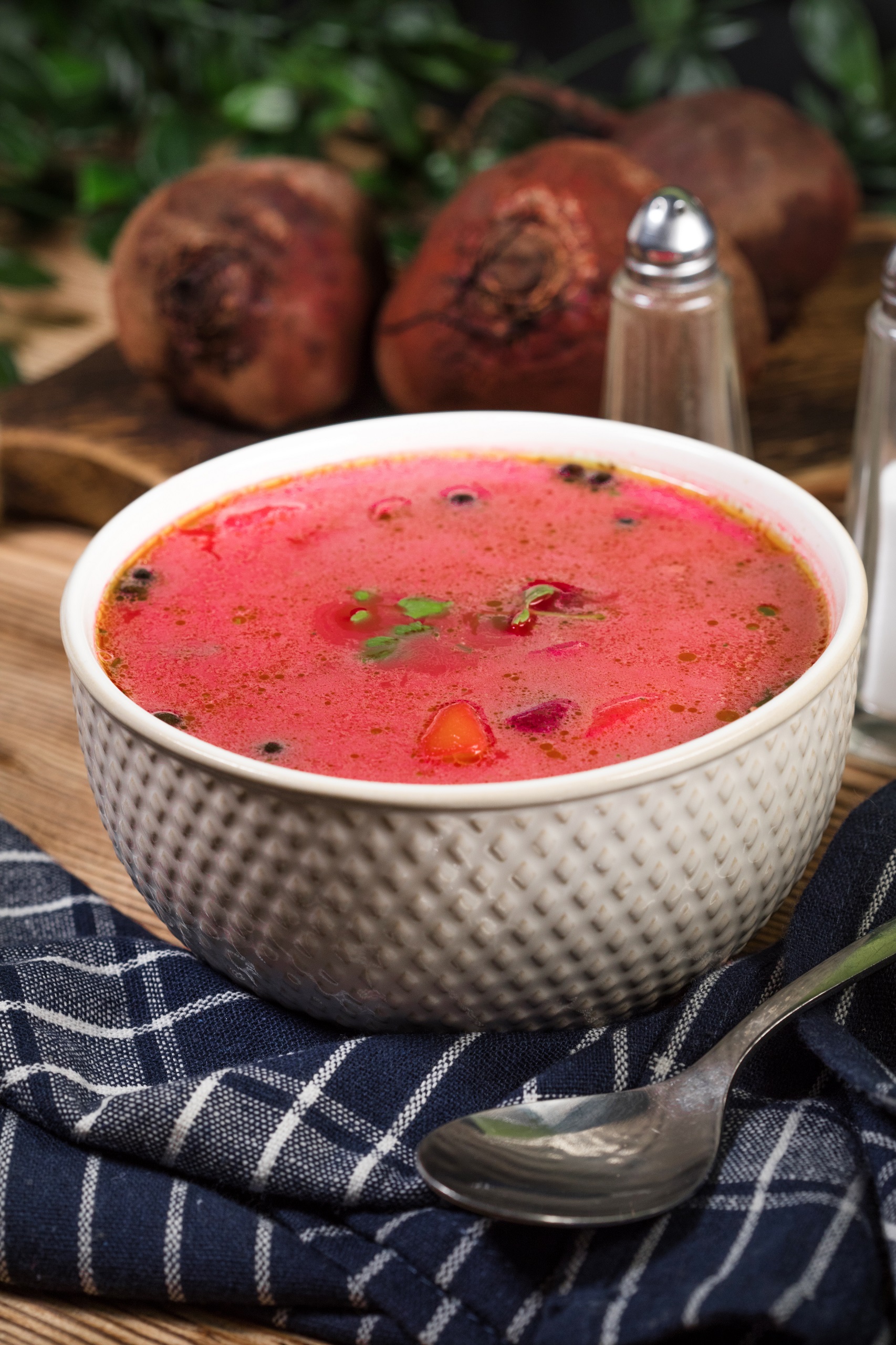 Red borscht soup in white bowl on wooden background.