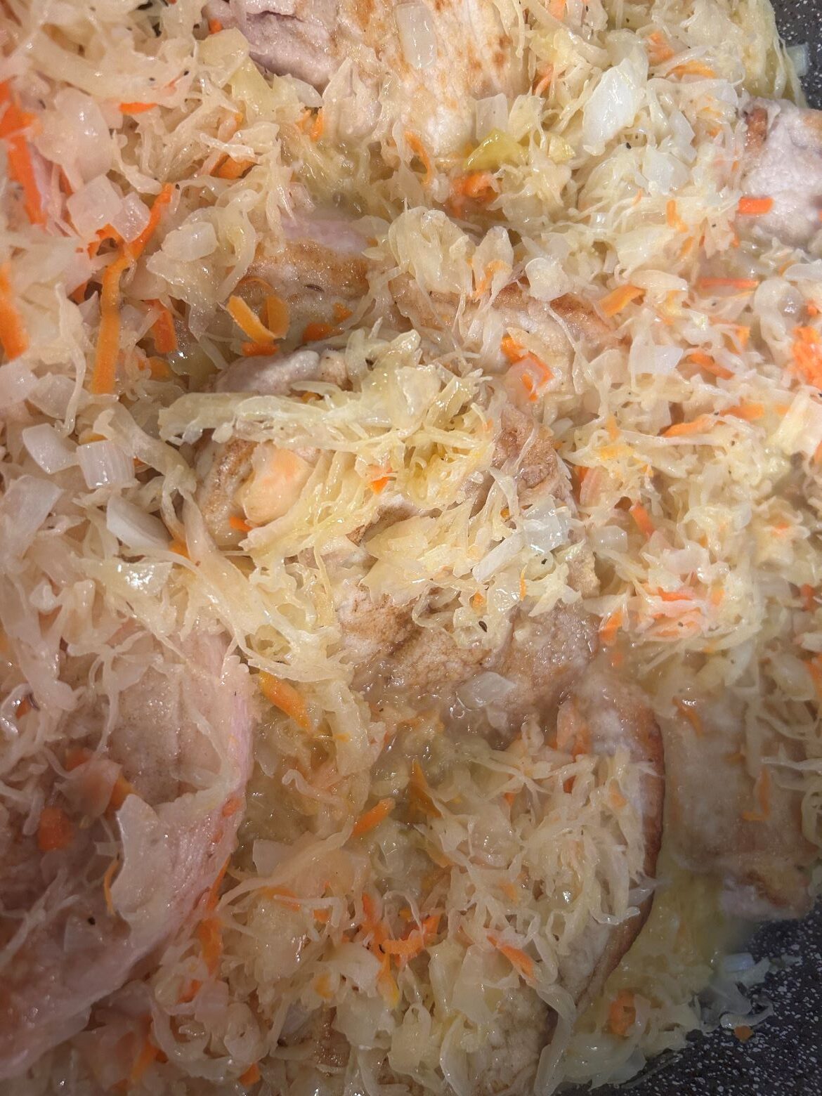 Kat's tangy sauerkraut and flavorful pork with the tiny carrot slices and seasoning visible in natural juices in the pan used to make it.