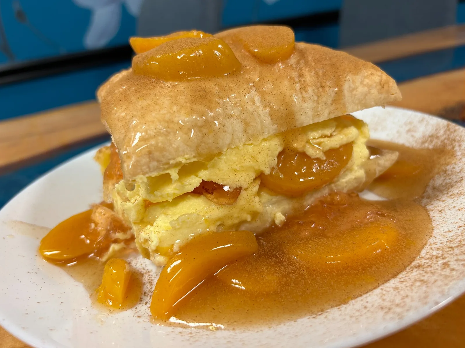 Close-up of Kat’s Café Slavic Napoleon layered with cream and peaches, topped with peach sauce and cinnamon.