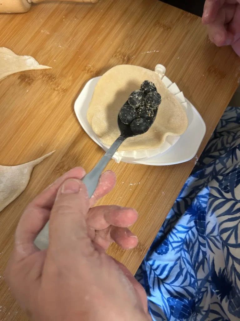 Fresh blueberries being placed onto a thin round of scratch-made pierogi dough before each pierogi is folded and sealed by hand at Kat’s Café & Restaurant.