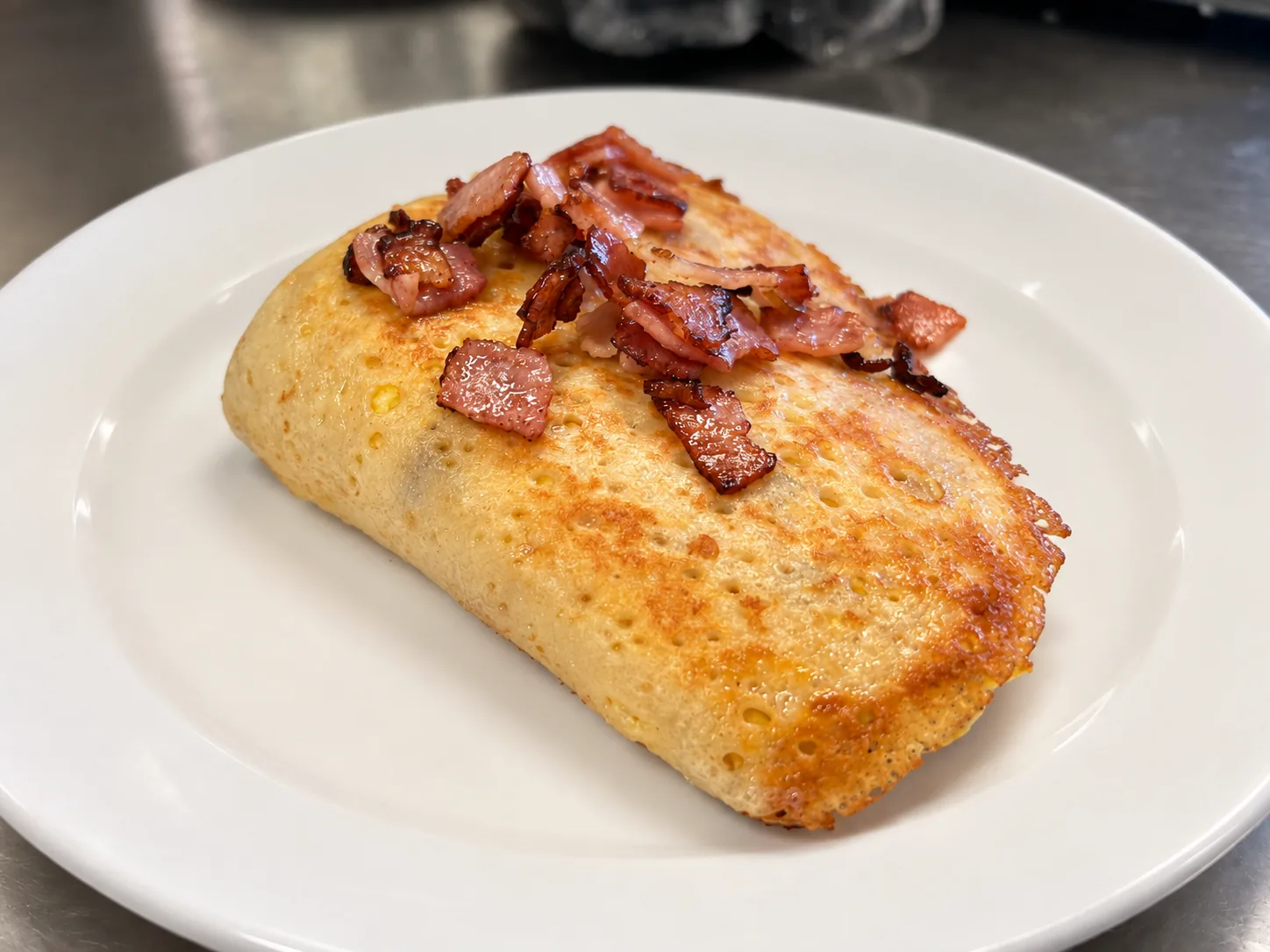 Lightly browned ham, egg and cheese crepe at Kat’s Café & Restaurant, topped with pieces of pan-fried ham, served on a white plate.