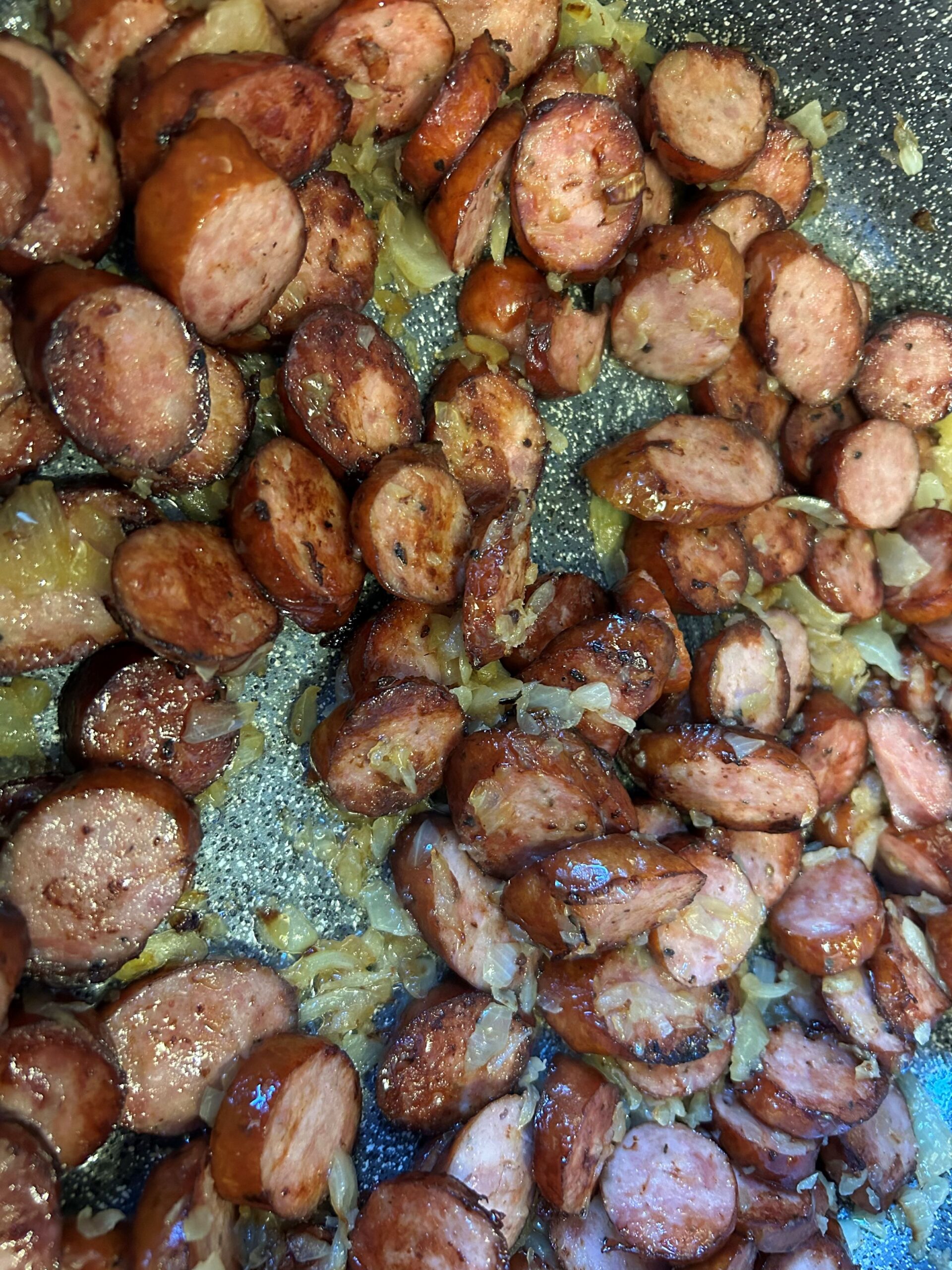 Kat's Letcho Kielbasa Pieces Being Made with Onions in a pan as they cook.