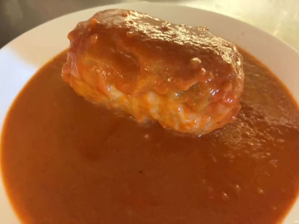 Fresh Halupki Smothered in Homemade Tomato Sauce served on a white plate.