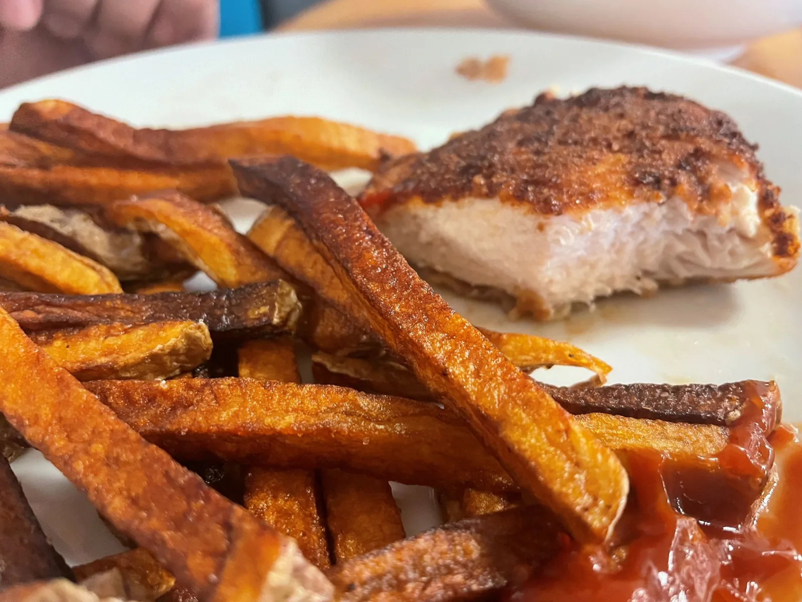 Close-up of a breaded chicken cutlet at Kat’s Café & Restaurant, cut open to show the white meat, served with hand-cut fries and ketchup on a white plate.