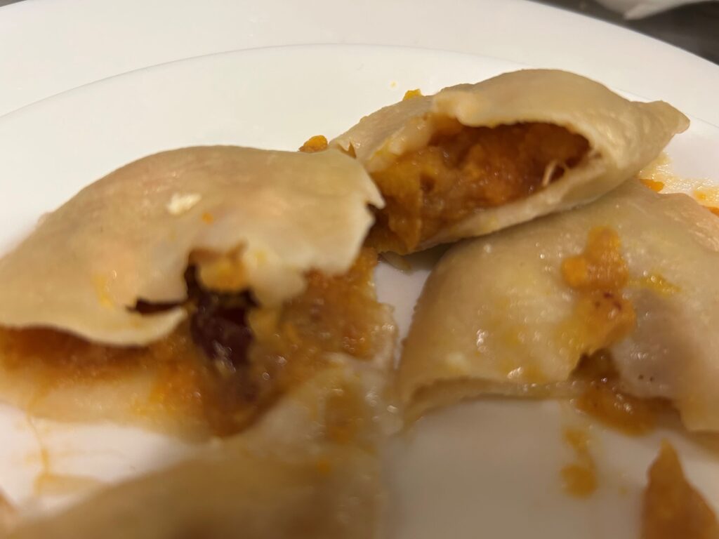 Photo of Kat's Pilgrims Pierogis cut in half showing the all-natural filling, on a white plate.