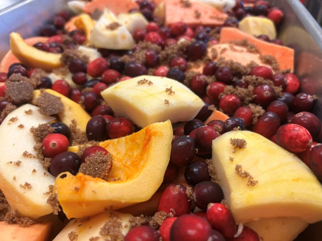 A photo of Kat's Pilgrims Pierogi Filling Before Being Placed in the Oven with Lots of Fresh Cranberries, Sliced Pears, Pieces of Pealed Pumpkin, Sweet Potato Halves, the Entire Top of the Produce Sprinkled with a Generous Amount of Freshly Made Cinnamon Sugar.