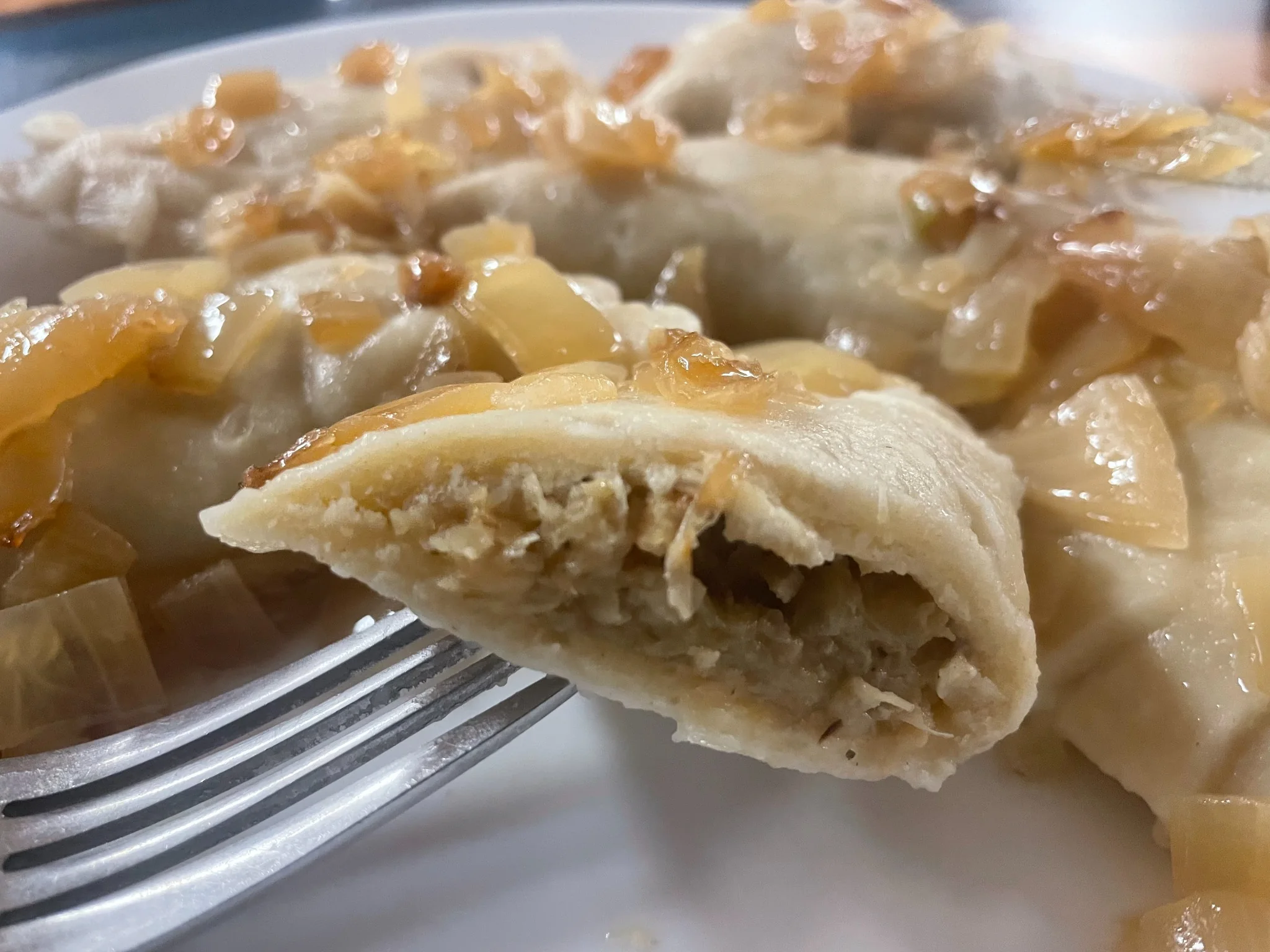 Close-up of a cabbage and mushroom pierogi cut open to show the filling, with caramelized onions at Kat’s Café & Restaurant.