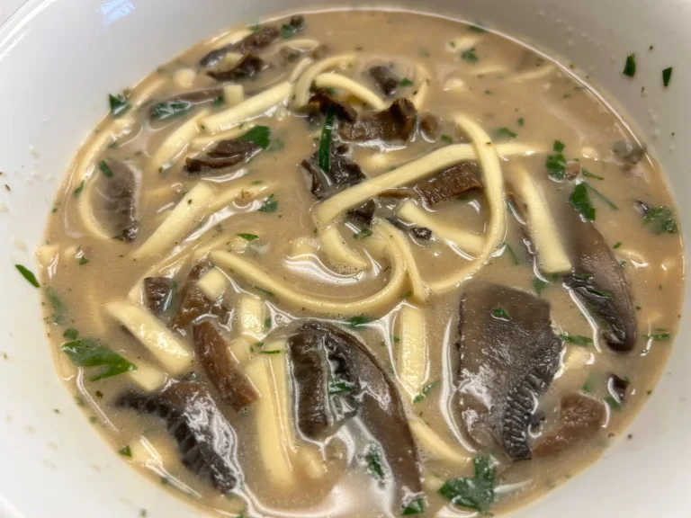 Creamy wild mushroom soup with noodles, sliced mushrooms, and chopped herbs in a white bowl at Kat’s Café & Restaurant.
