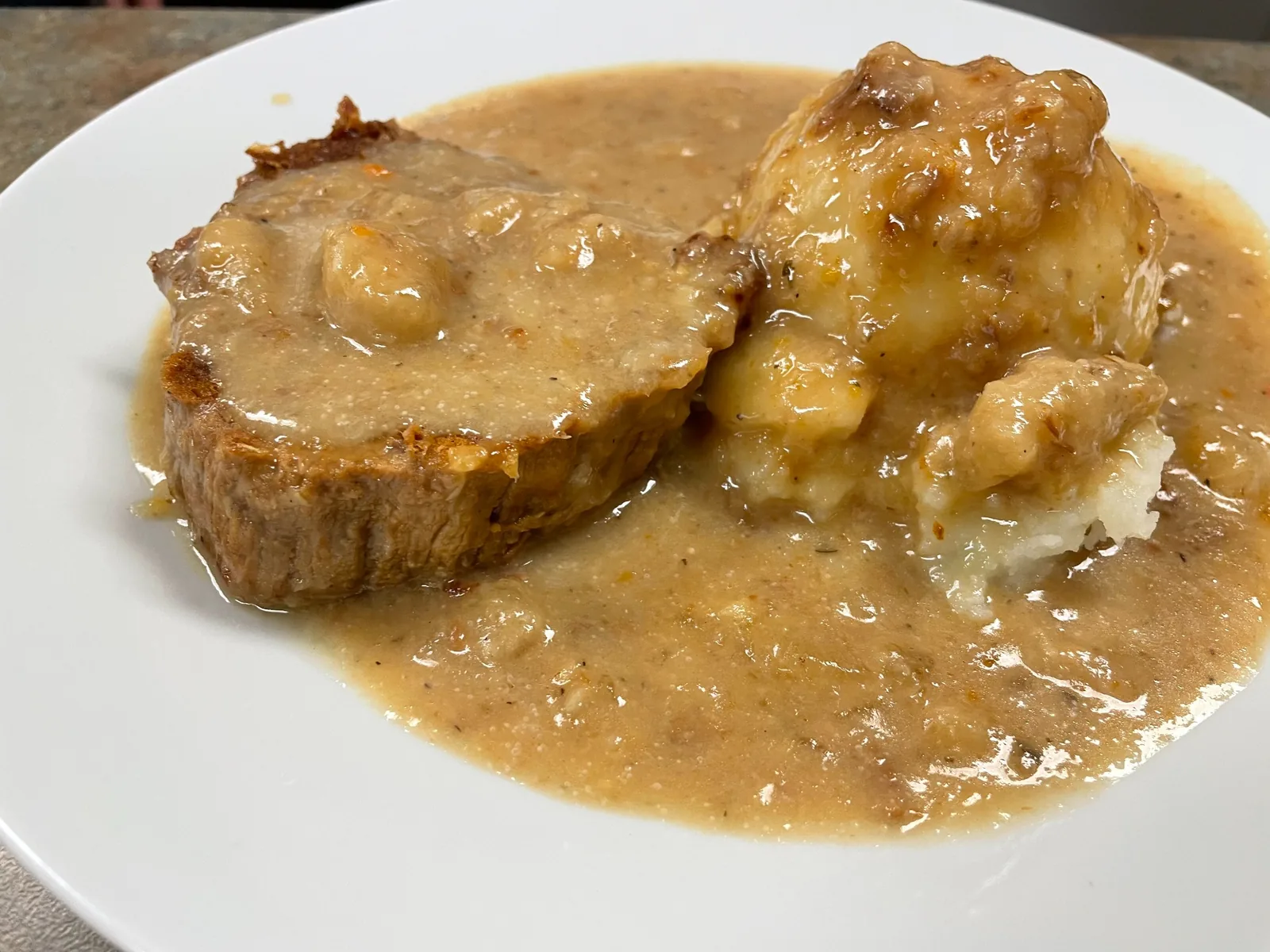 Thick slices of beef beside mashed potatoes, both covered in horseradish sauce on a white plate at Kat’s Café & Restaurant.