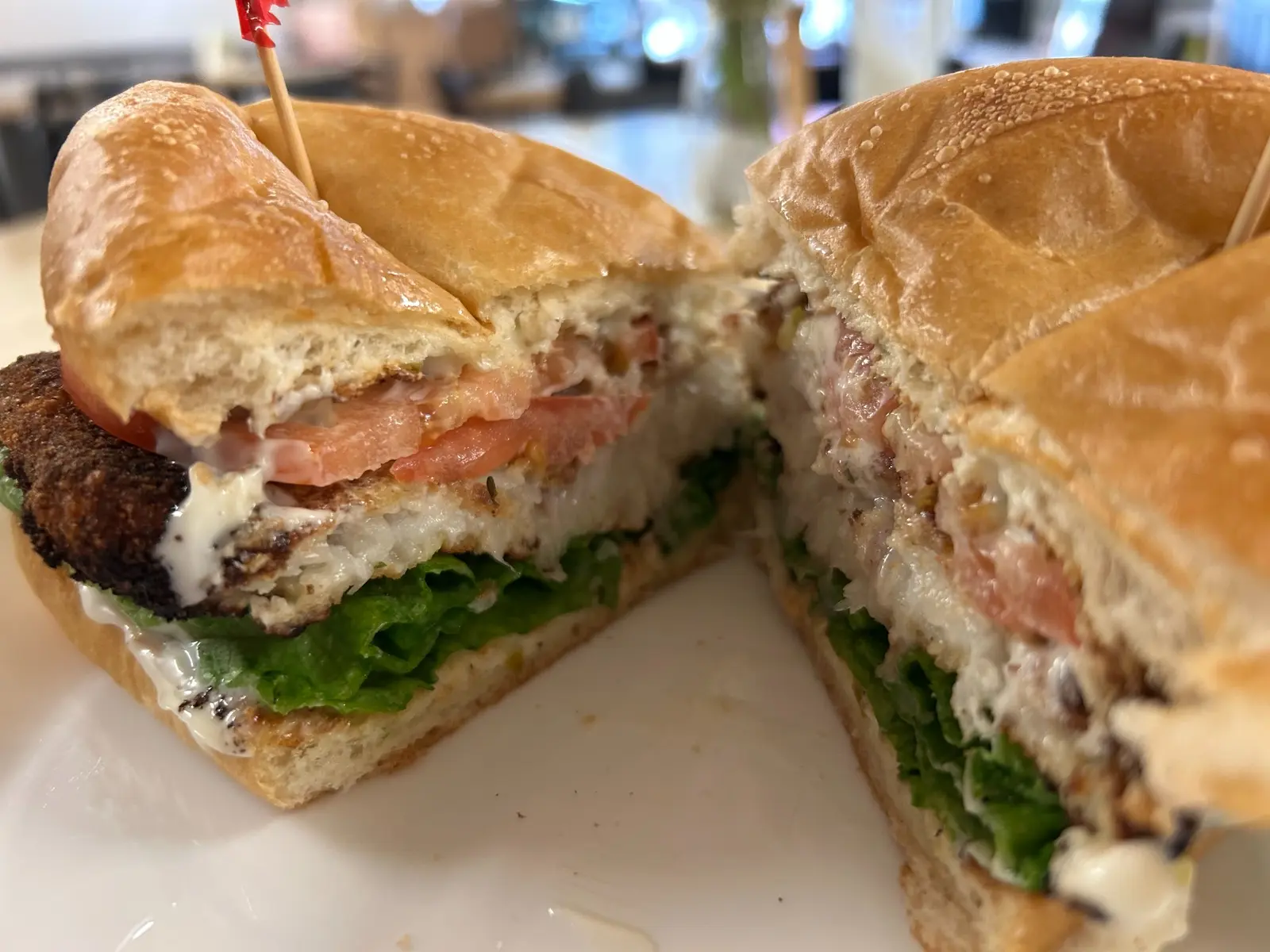 Fish fillet sandwich at Kat’s Café & Restaurant, cut in half with pan-fried breaded fish, homemade tartar sauce, lettuce, and tomato on a bakery roll.