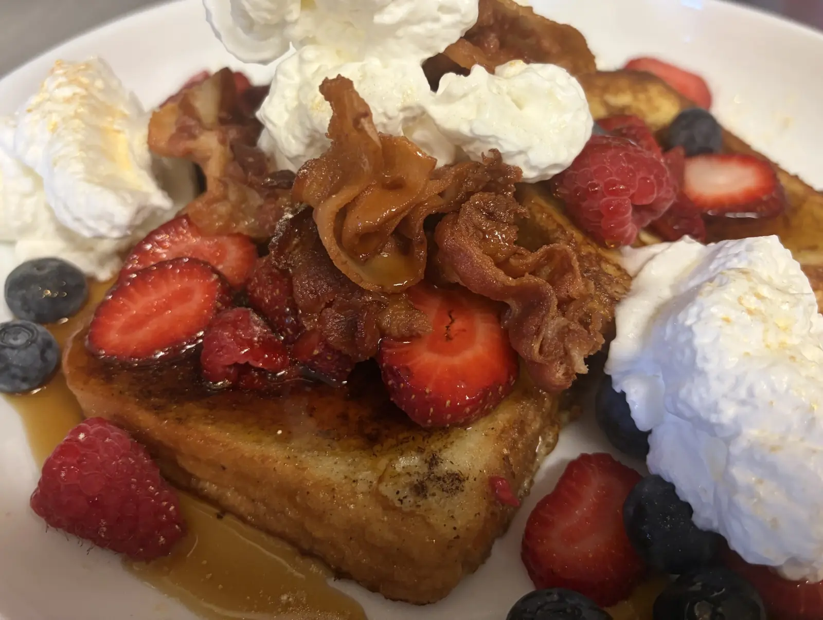 French toast topped with fresh strawberries, blueberries, raspberries, bacon, and generous portions of whipped cream. at Kat’s Café & Restaurant.