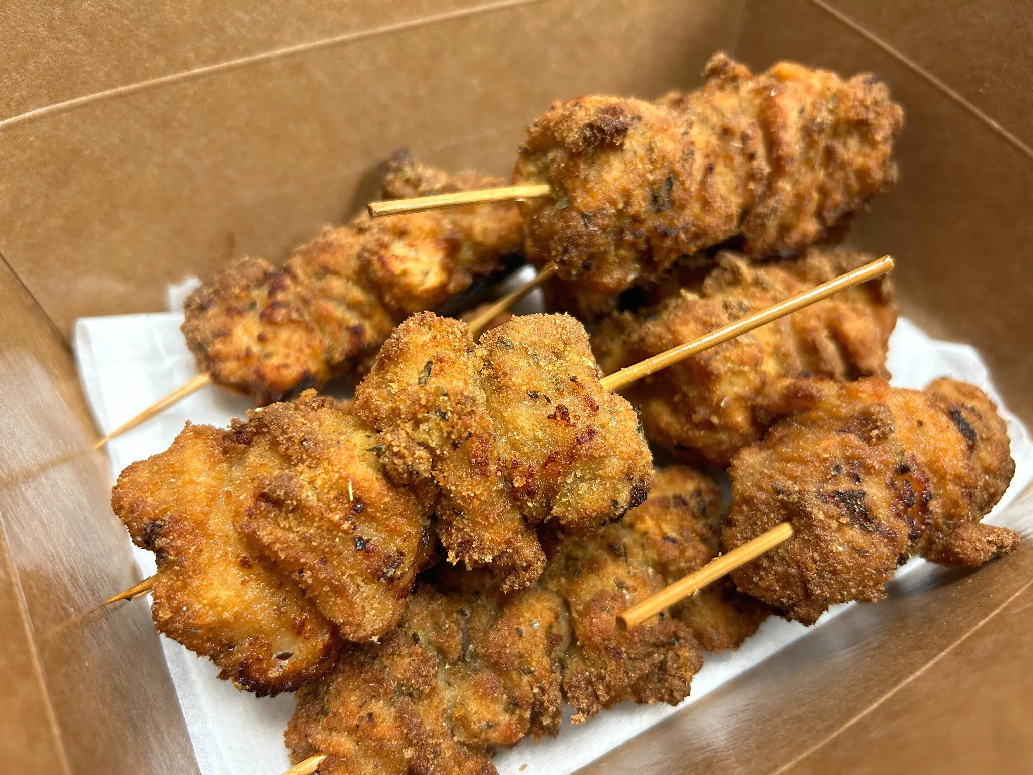 Golden-brown chunk-style City Chicken arranged on wooden skewers inside a takeout box from Kat’s Café & Restaurant.