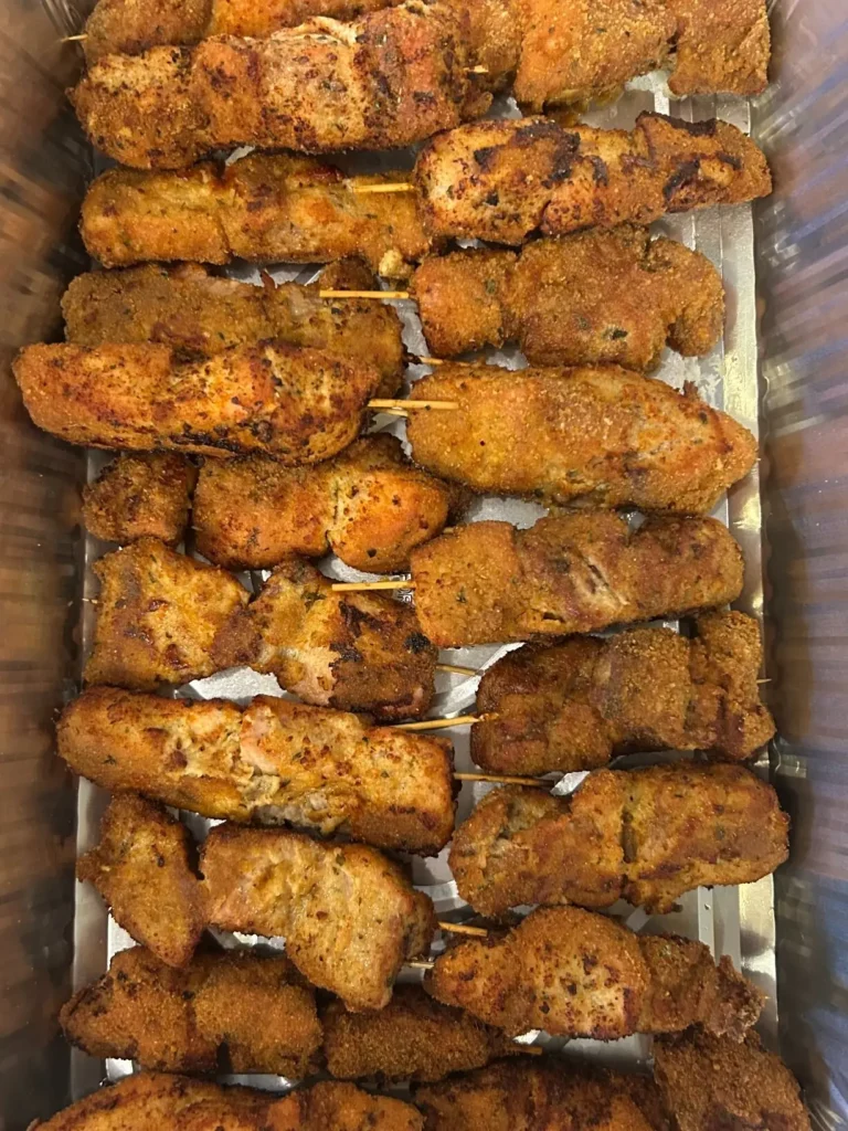 Overhead view of a large catering tray filled with golden-brown chunk-style City Chicken skewers from Kat’s Café & Restaurant.