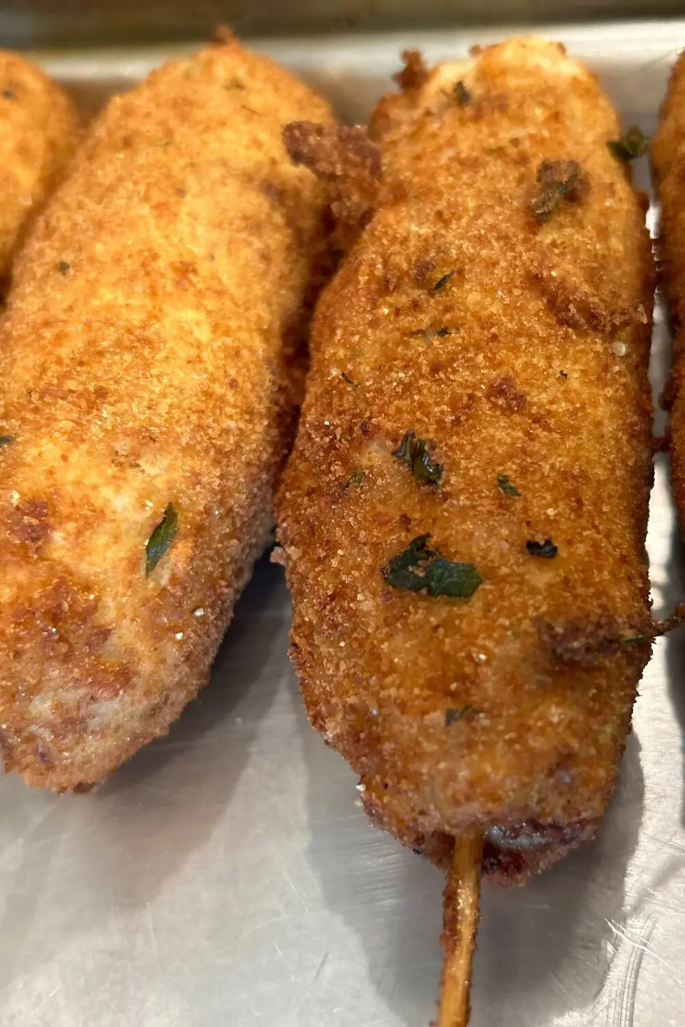 Close-up of golden-brown, lightly breaded ground-style City Chicken formed on wooden skewers and arranged on a metal tray at Kat’s Café & Restaurant.
