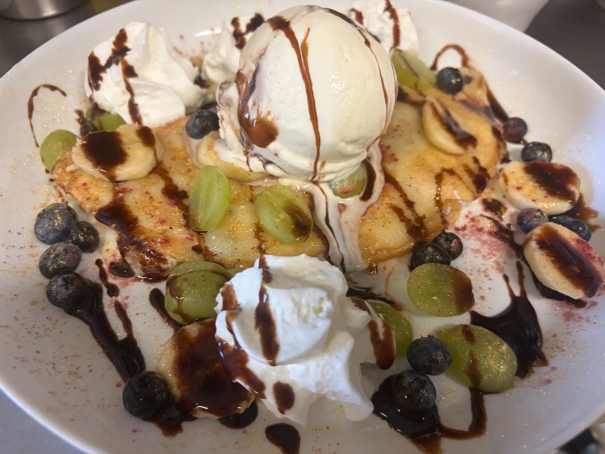 Polish-style crepes topped with vanilla ice cream, whipped cream, banana slices, blueberries, grapes, and chocolate drizzle at Kat’s Café & Restaurant.