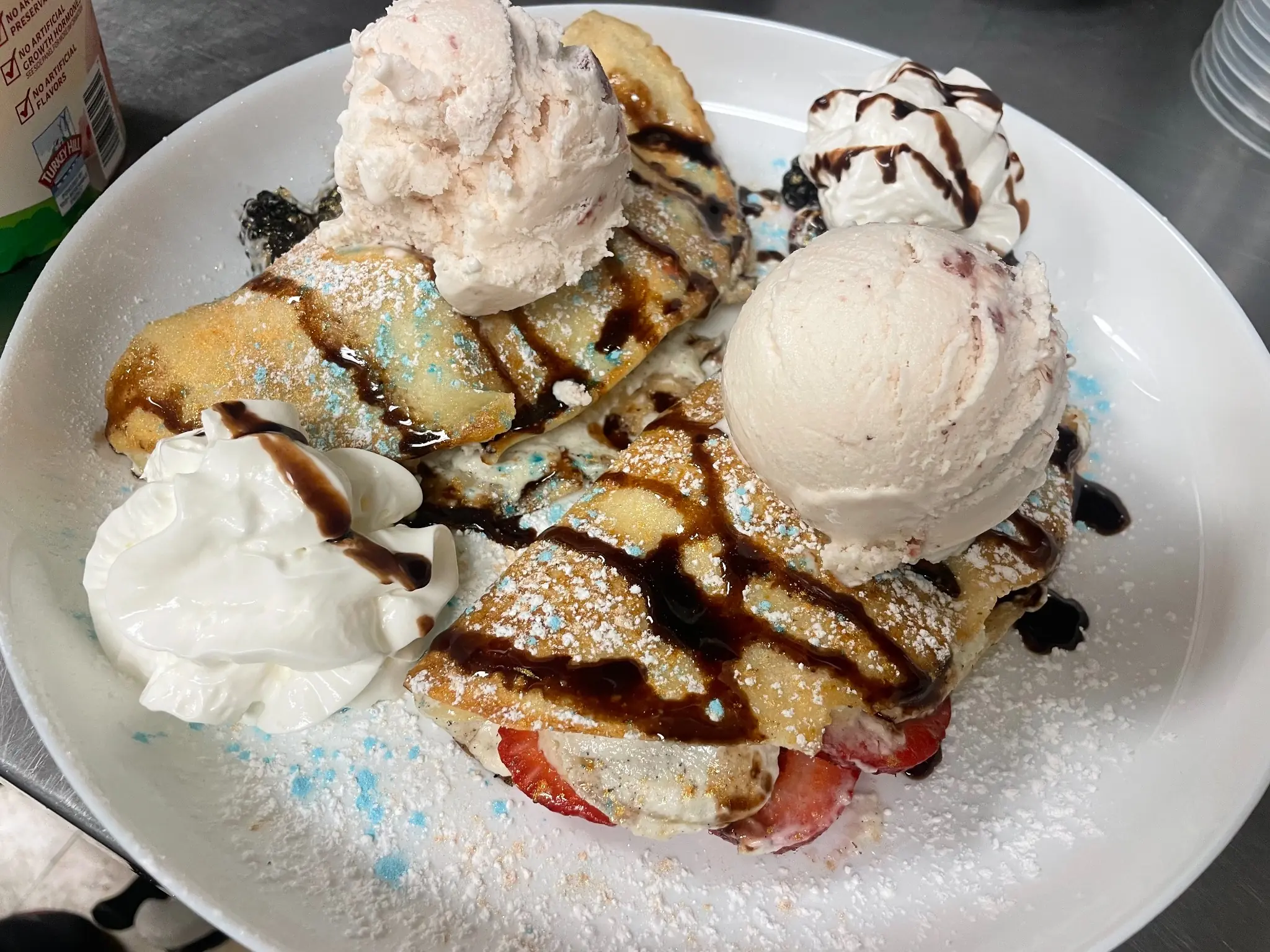 Strawberry-filled sweet cheese Polish crepes topped with strawberry ice cream, whipped cream, powdered sugar, and chocolate drizzle at Kat’s Café & Restaurant.