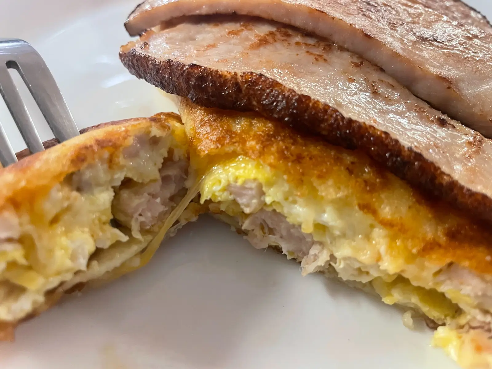 Close-up of a browned pan-seared turkey, egg and cheese breakfast blintz cut open and topped with thick slices of grilled turkey at Kat’s Café & Restaurant.
