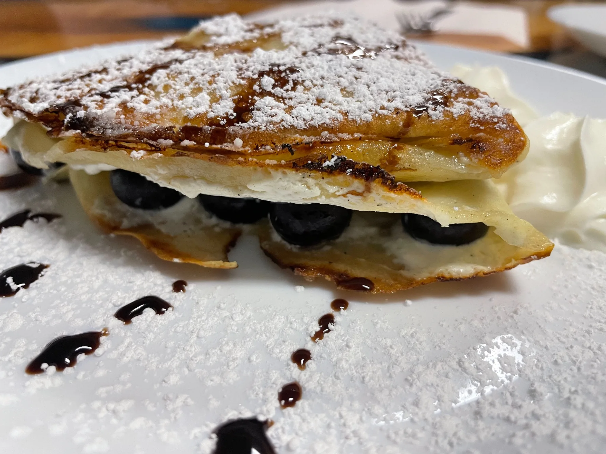 Folded crepe filled with vanilla sweet cheese and whole blueberries, dusted with powdered sugar and finished with chocolate drizzle at Kat’s Café & Restaurant.