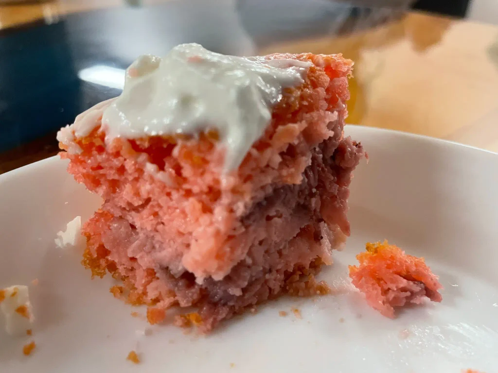 Close-up of the soft, fruit-filled interior of a partially eaten strawberry banana mini cake topped with white frosting at Kat’s Café & Restaurant.