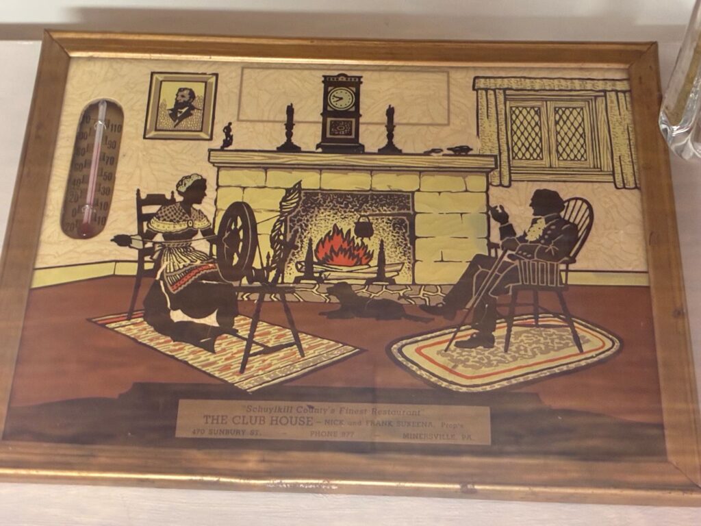Historical Engraving and Plated Artwork in Colors of Schuylkill County's Finest Restaurant known as the Club House depicting a pre-Victorian couple seated across from one another as if in their living room in front of a brick fireplace with the fire lit, having the gentleman dressed in fine wear including a ruffled collar while holding a cane sitting on a chair making a hand gesture as if speaking to the female sitting across from him dressed in a lady's reputable home attire of that time seated in front of a spindle with a string of yarn being pulled by her hand with the silhouette of a dog laying on the floor between them, having items on the brick mantle including a grandmother's clock, candlestick with candles, a figurine, and a portrait of what might be Abe Lincoln on the wall, and a window with curtains also in the background.