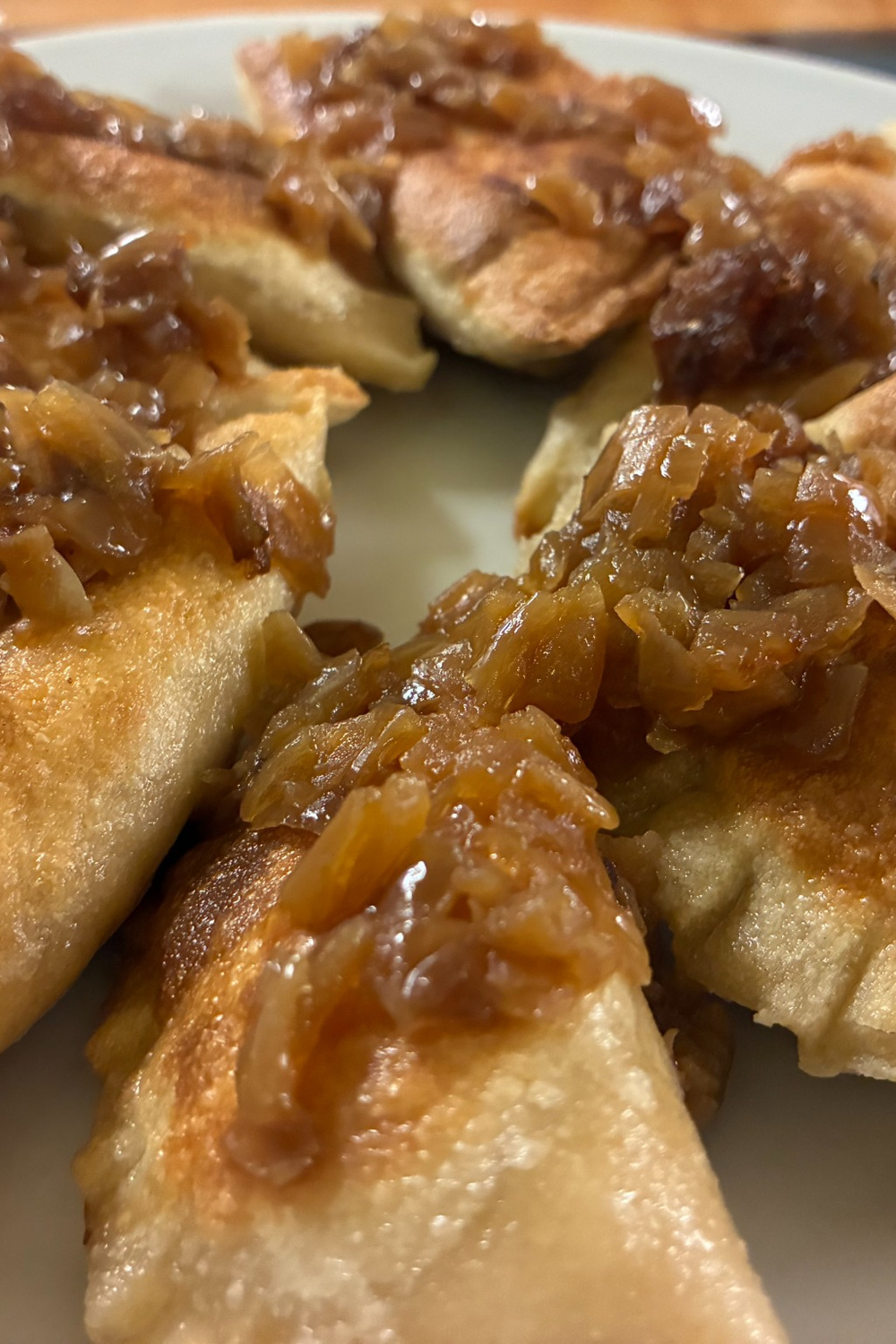 Close-up of golden pan-fried pierogies topped with caramelized onions on a white plate at Kat’s Café & Restaurant.