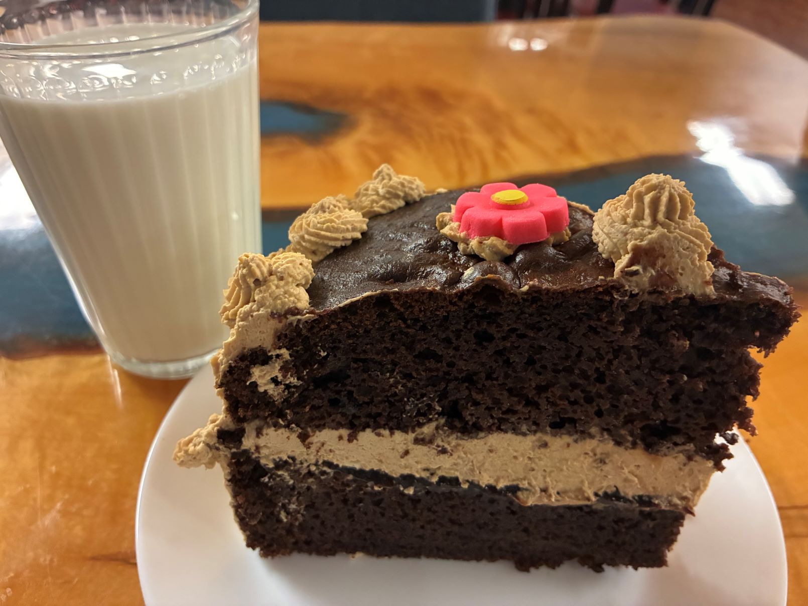 Kat's Slice of Coffee Creme Chocolate Cake with a Glass of Milk on the Custom Ambrosia Maple Wood Table at the Restaurant.