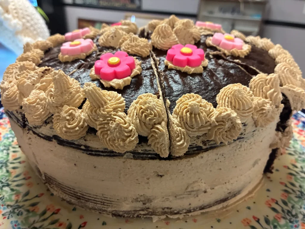 Whole chocolate cake with coffee crème frosting and pink flower decorations at Kat’s Café & Restaurant.