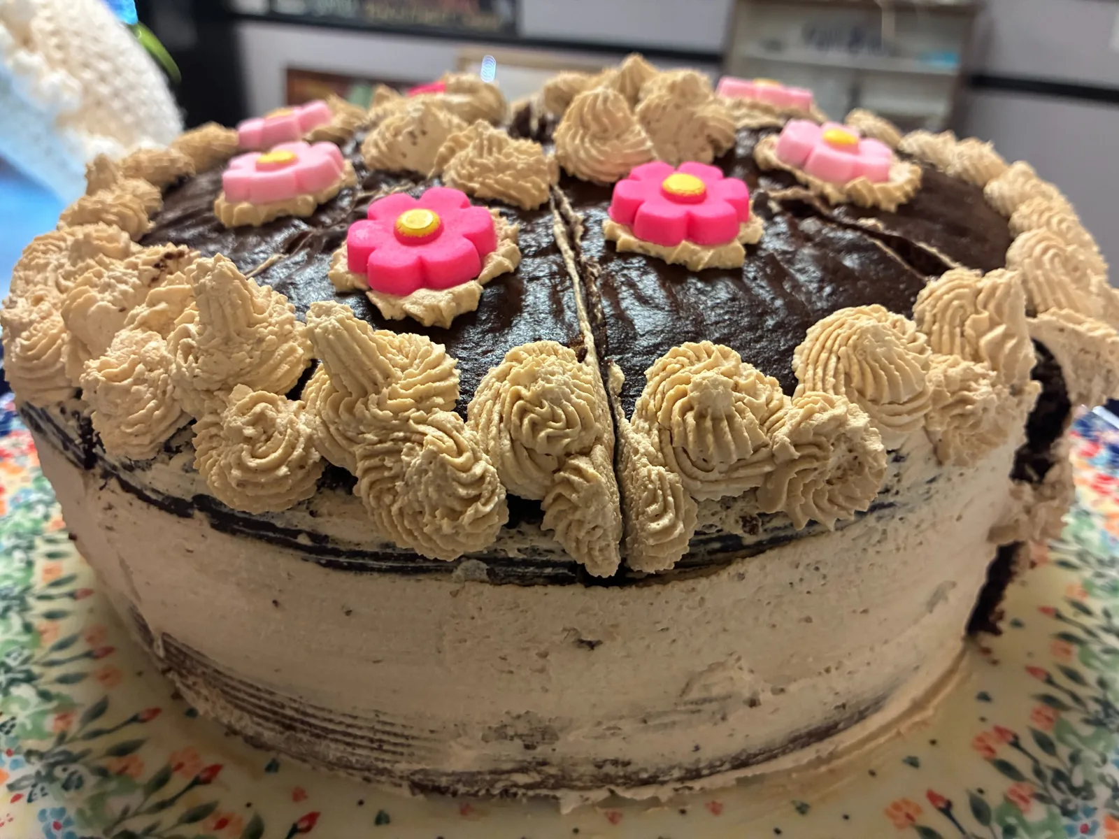 Whole chocolate cake with coffee crème frosting and pink flower decorations at Kat’s Café & Restaurant.