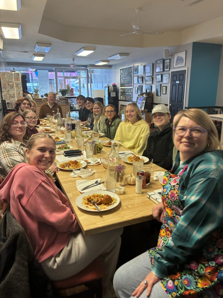 A photo of university students sitting around a long table during a private event at the restaurant with plates of food.