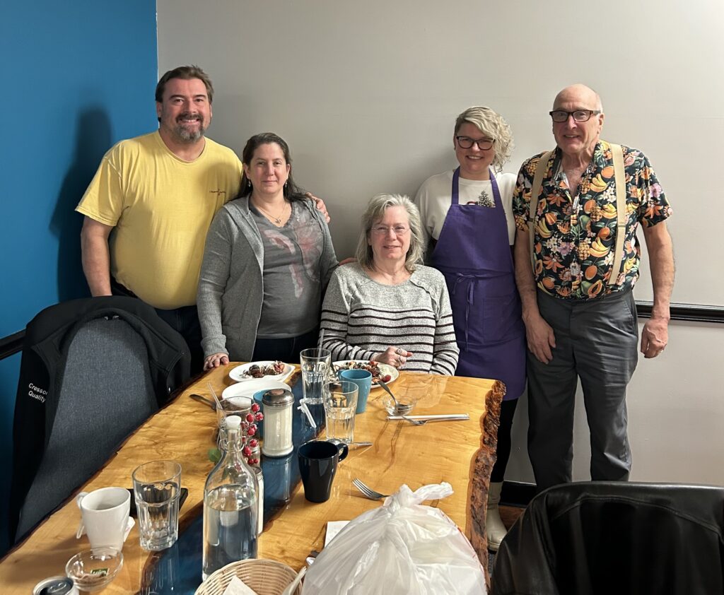 A photo of a group of happy customers standing behind the custom maple ambrosia table with Kat.