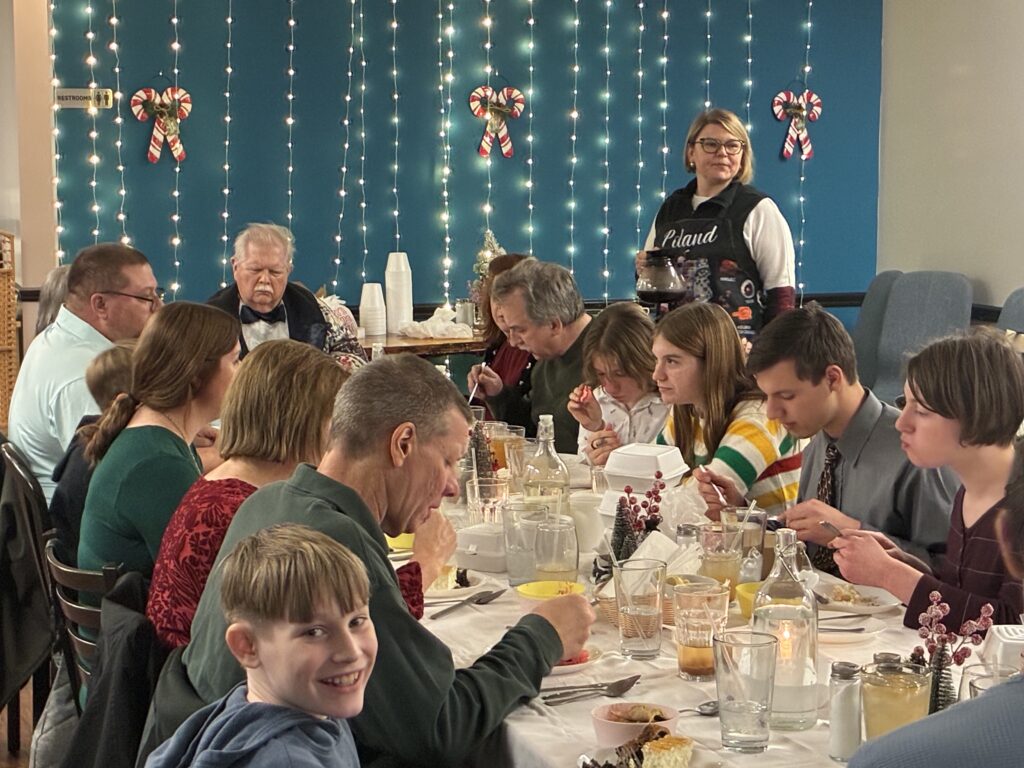 Kat's 2nd Annual Christmas Eve Holy Supper Wigilia Event in Minersville, PA with Chef Kat looking over her guest happily eating their food and enjoying themselves around the vigil feast table.