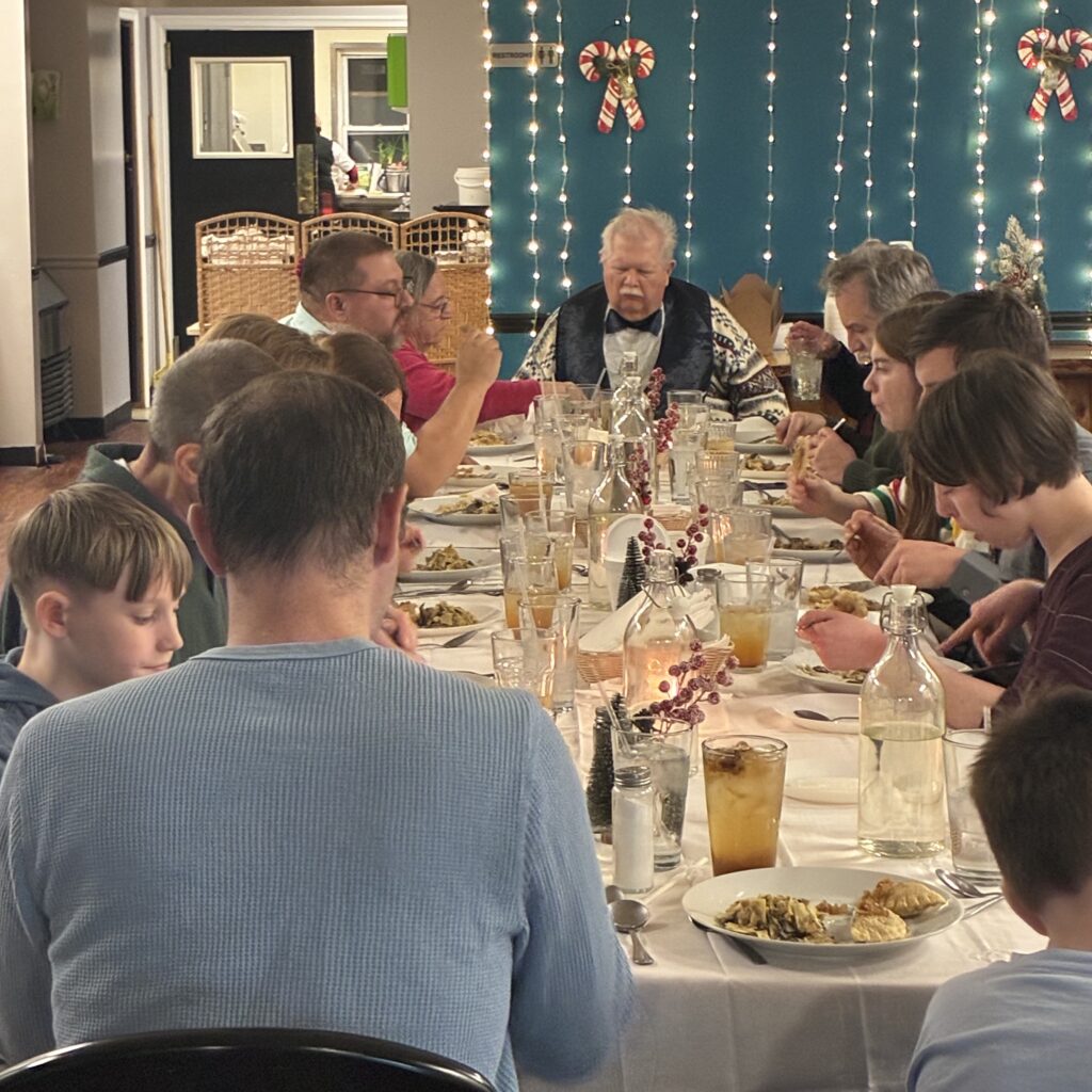 Kat's Holy Supper Spread for the 2nd Annual Christmas Eve Event on the Adorned Festive Table with Guest Eating from their plates.