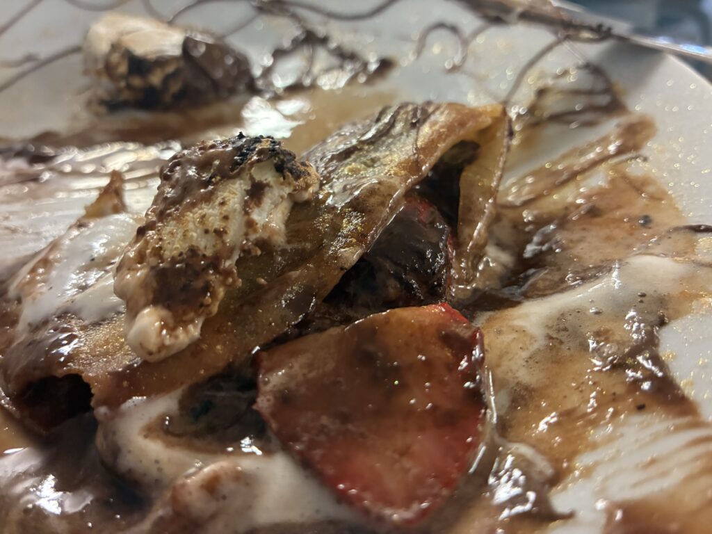 Strawberry Nutella S'mores Blintz with the different ingredients such as the hazelnut spread, fresh strawberries, crepe wrap, on a white plate.