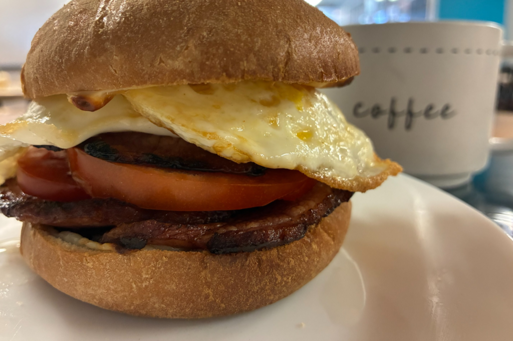 Ham and fried egg breakfast sandwich served on a plate with coffee at Kat’s Café & Restaurant.
