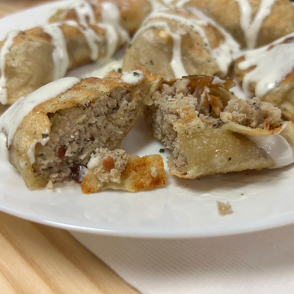 Pierogi drizzled with ranch; a cut-open pierogi shows a creamy chicken-and-bacon filling.