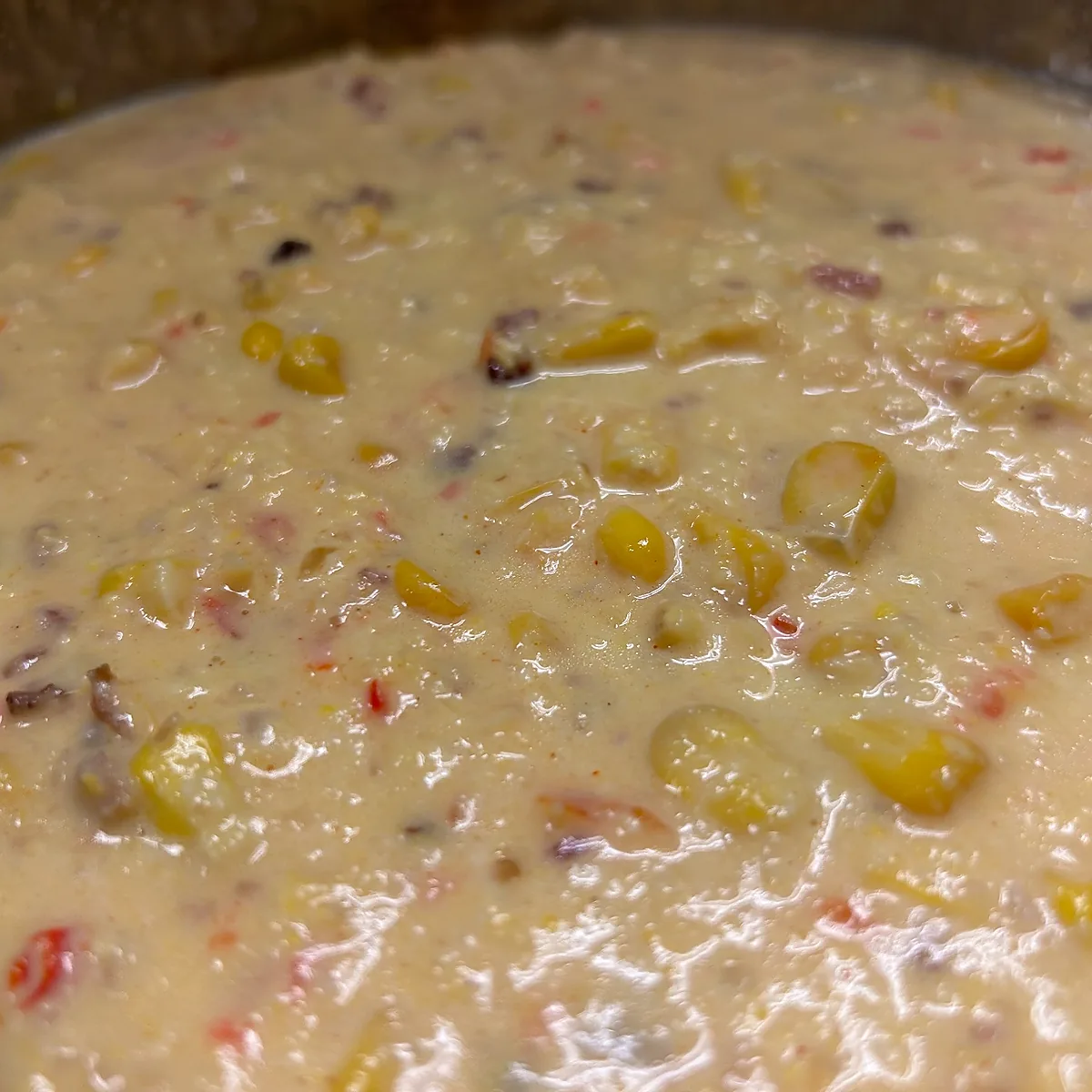 Close-up of creamy bacon corn chowder with visible corn kernels and a thick, hearty texture.