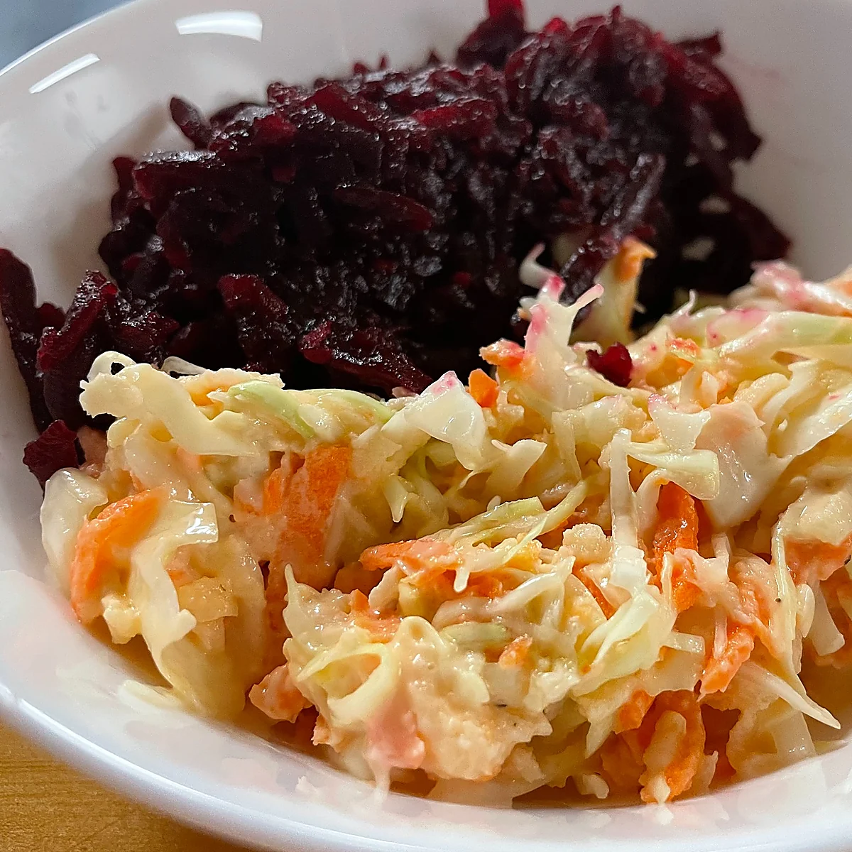 Bowl with shredded beets and creamy coleslaw—two Slavic veggie side salads.