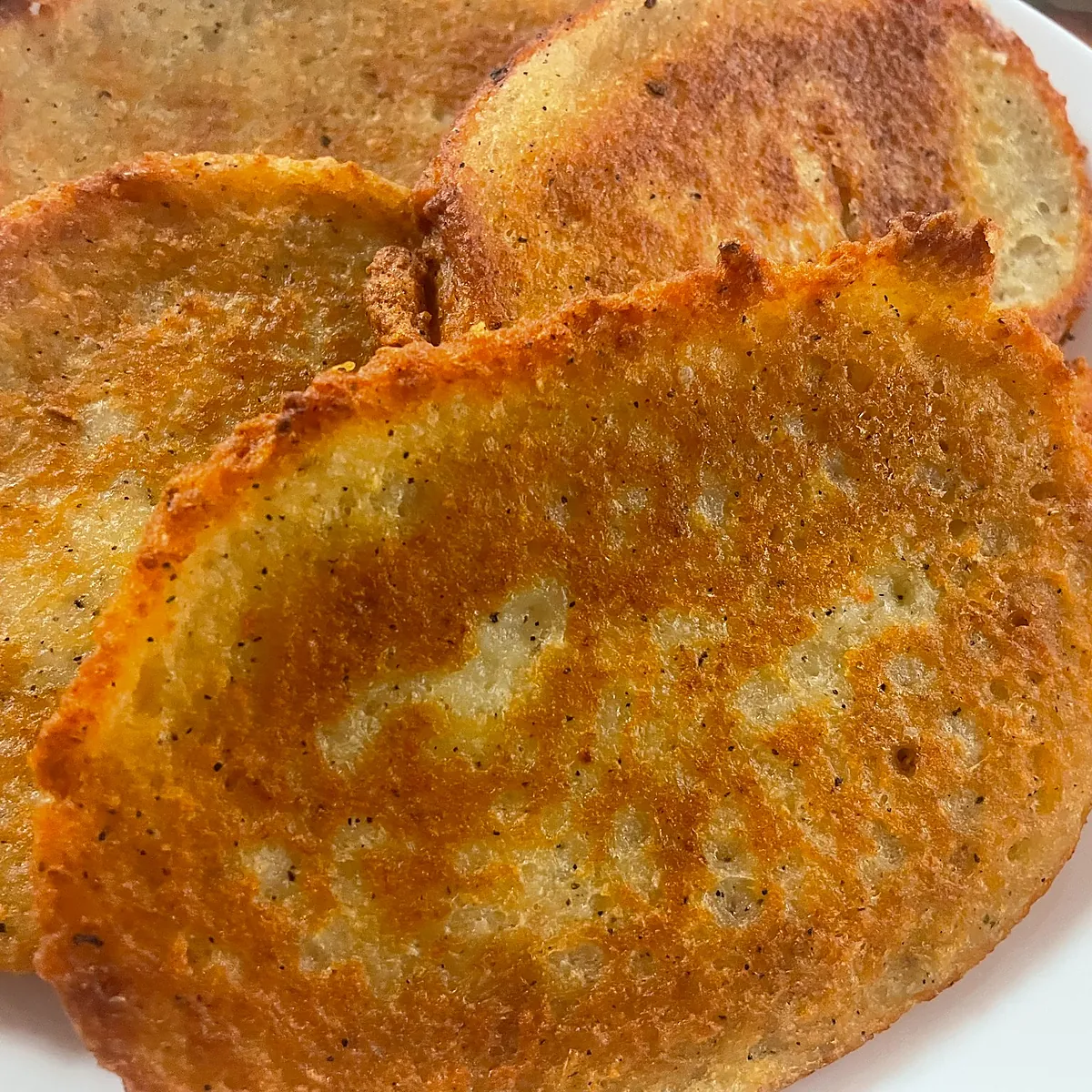 Golden-brown blinis stacked on a plate.