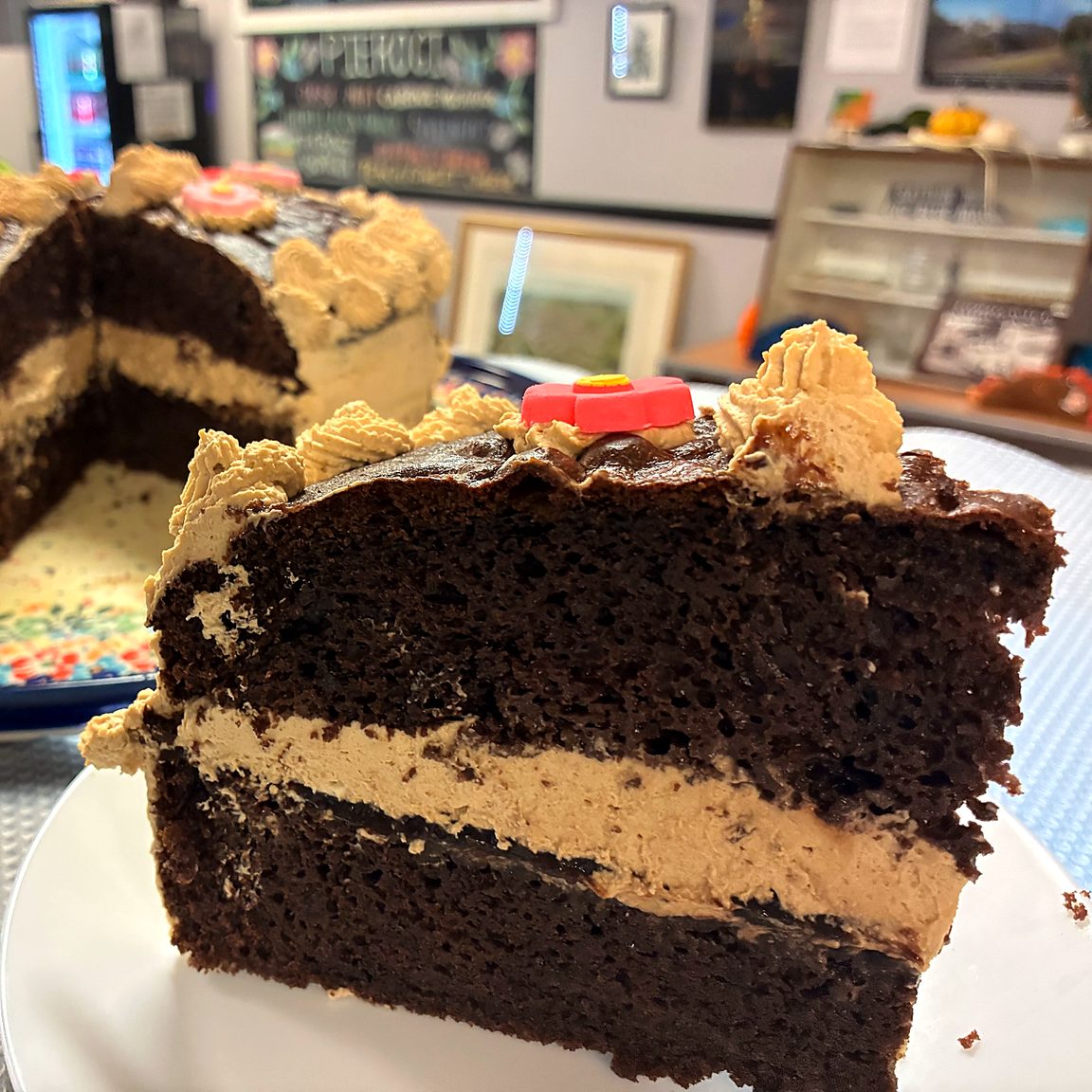 Slice of chocolate coffee crème cake with layered frosting, served on a plate in the café.