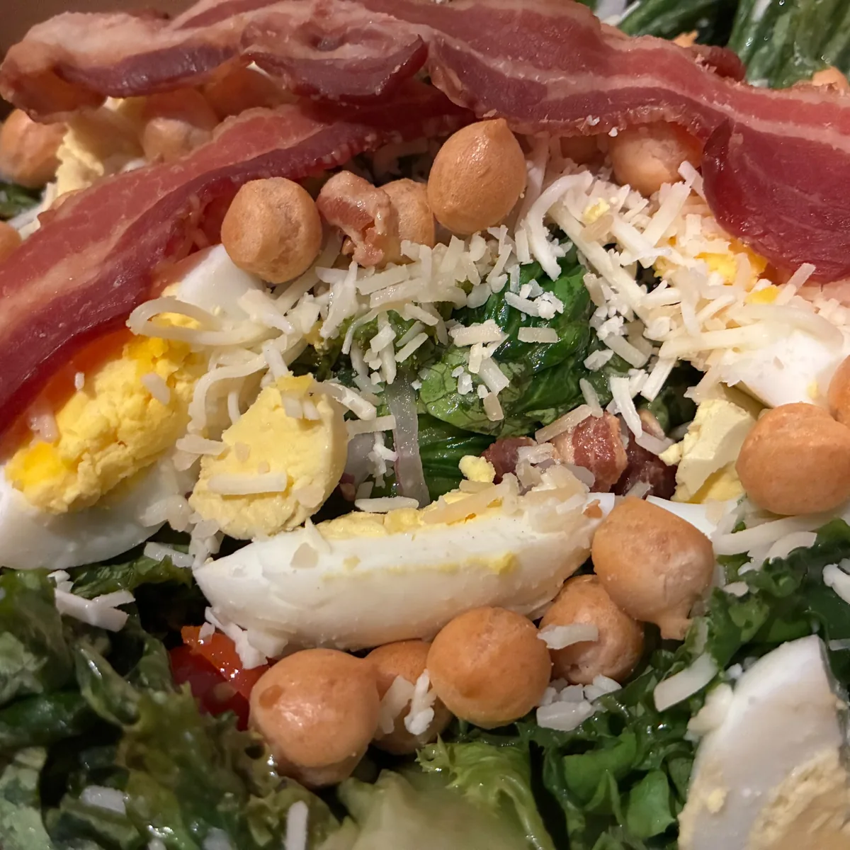 Classic Cobb salad with extra bacon, hard-boiled egg, shredded cheese, tomatoes, and crunchy toppings.