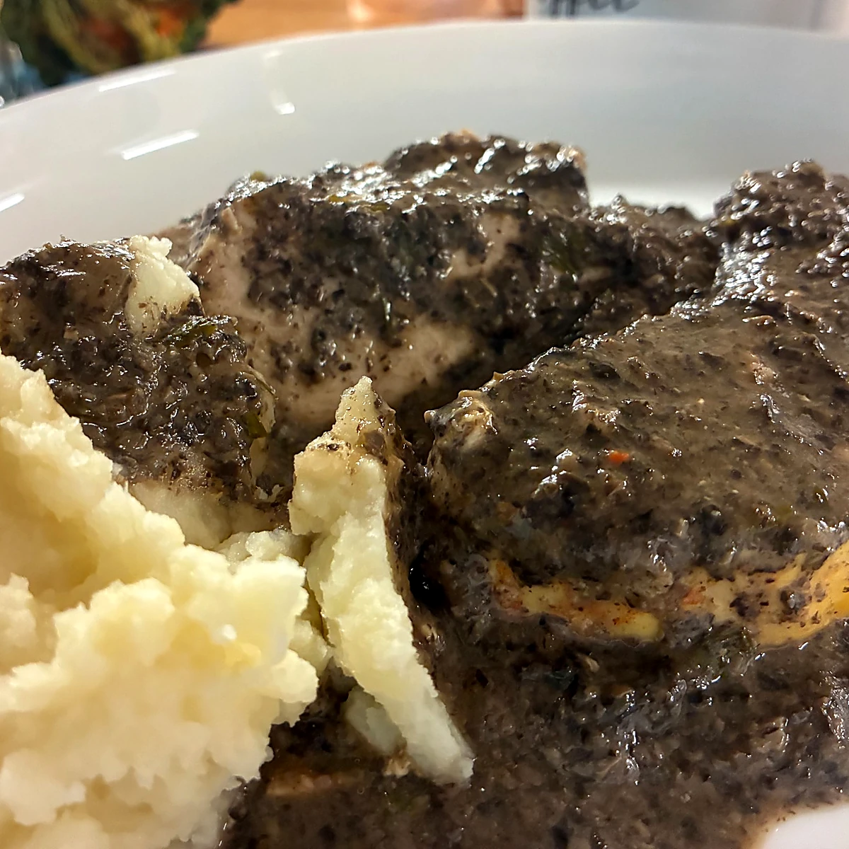 Creamy chicken and mushrooms served with mashed potatoes on a white plate.