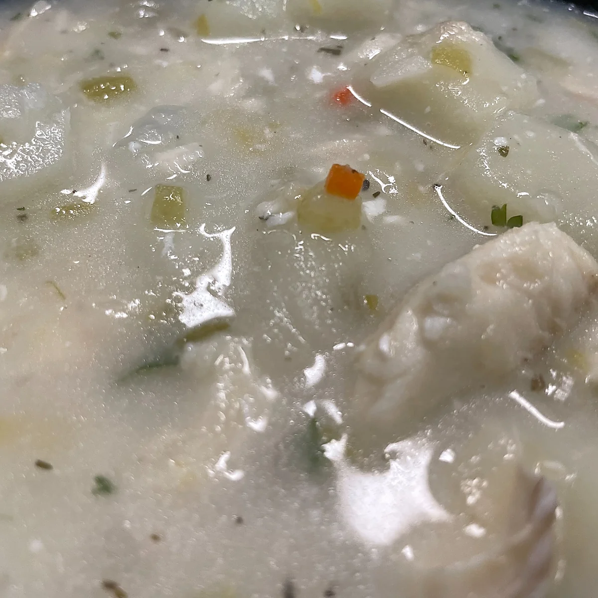 Close-up of creamy fish chowder with white fish, potatoes, and herbs.