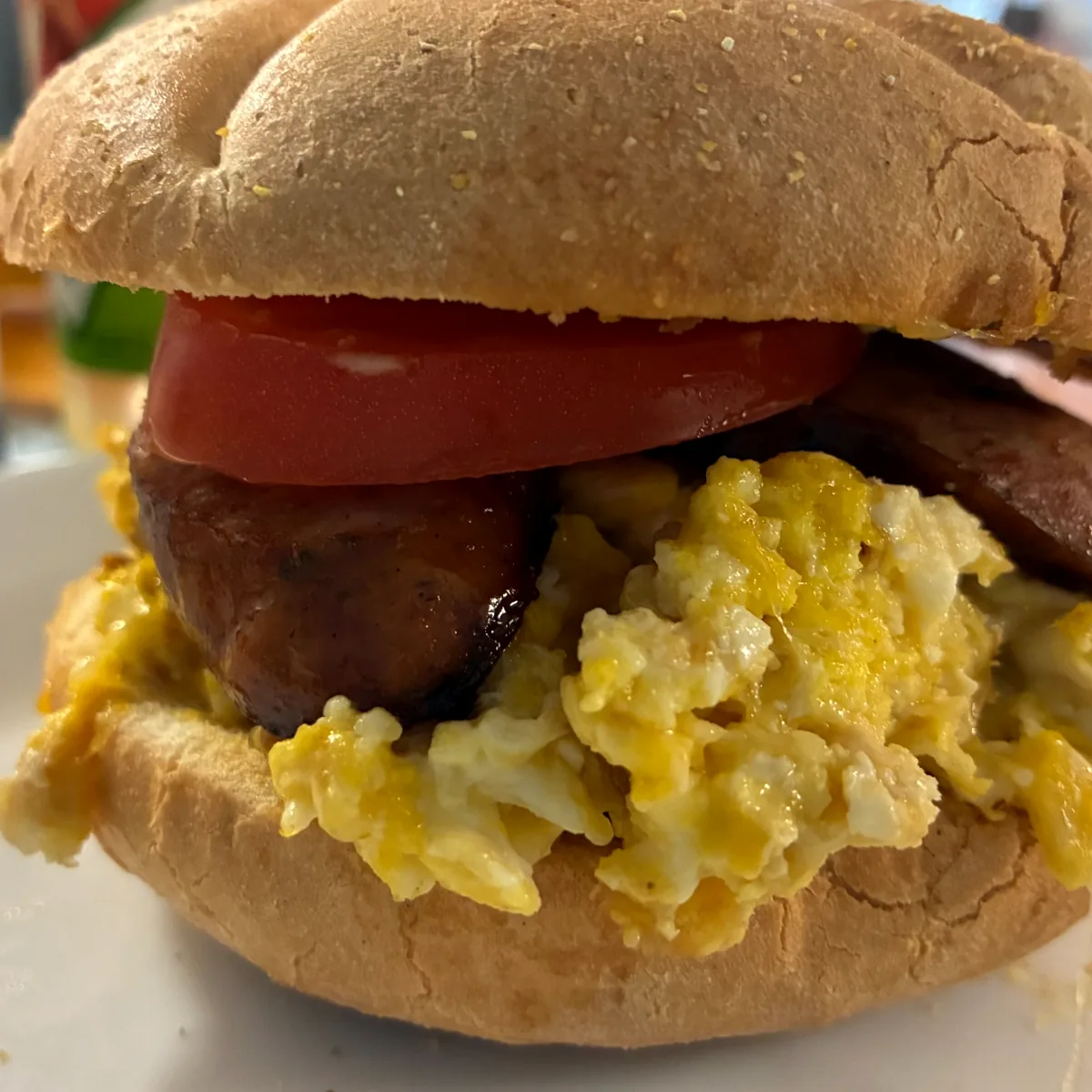 Kielbasa and scrambled egg sandwich with tomato on a roll.