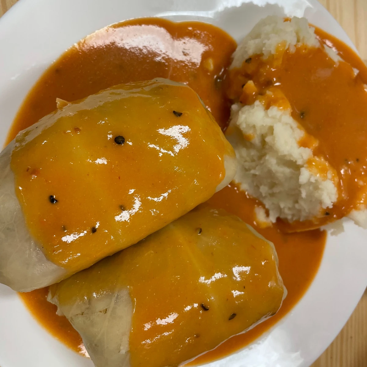 Stuffed cabbage rolls in sauce served with mashed potatoes on the side covered with sauce. Also known as "gołąbki."