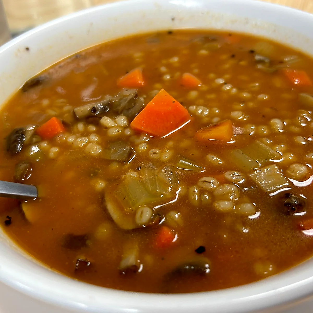 Bowl of mushroom barley soup with carrots, mushrooms, celery, and tender barley in a rich savory homemade broth.