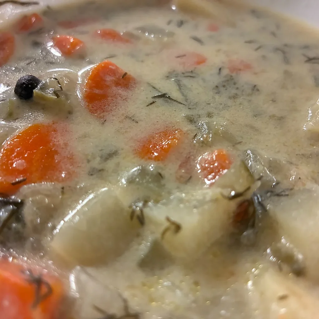 Close-up of creamy vegetable soup with potatoes, carrots, leeks, and herbs